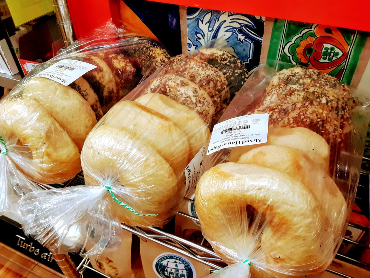 Bags of different flavored bagels are on a counter