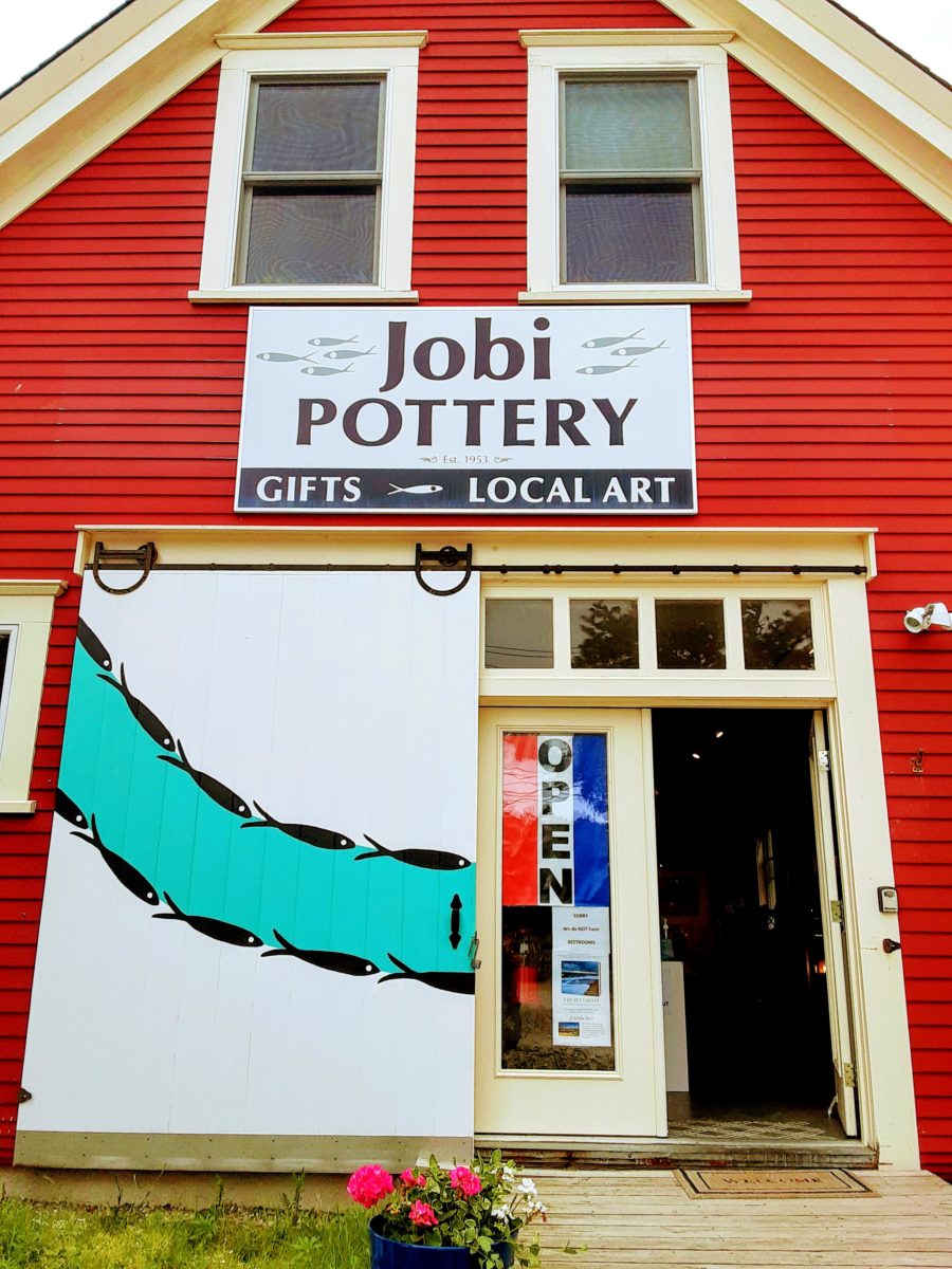 A red pottery building is shown with fish painted on the door