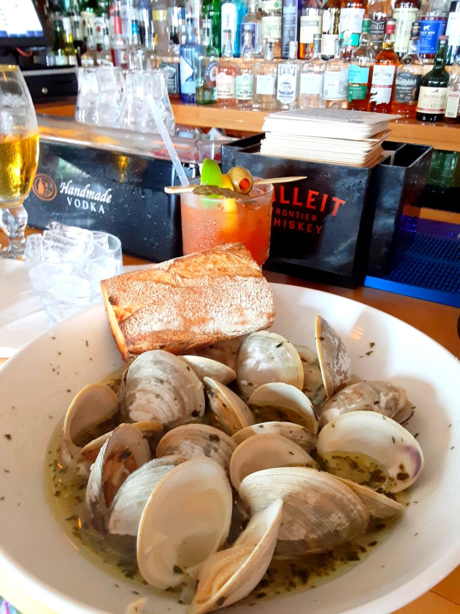 A bowl of steamed clams sits on a bar