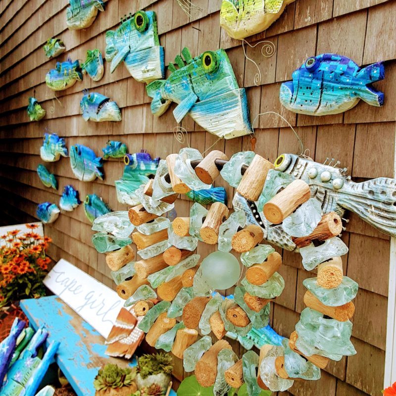 Seaglass garden art and wooden fish are shown