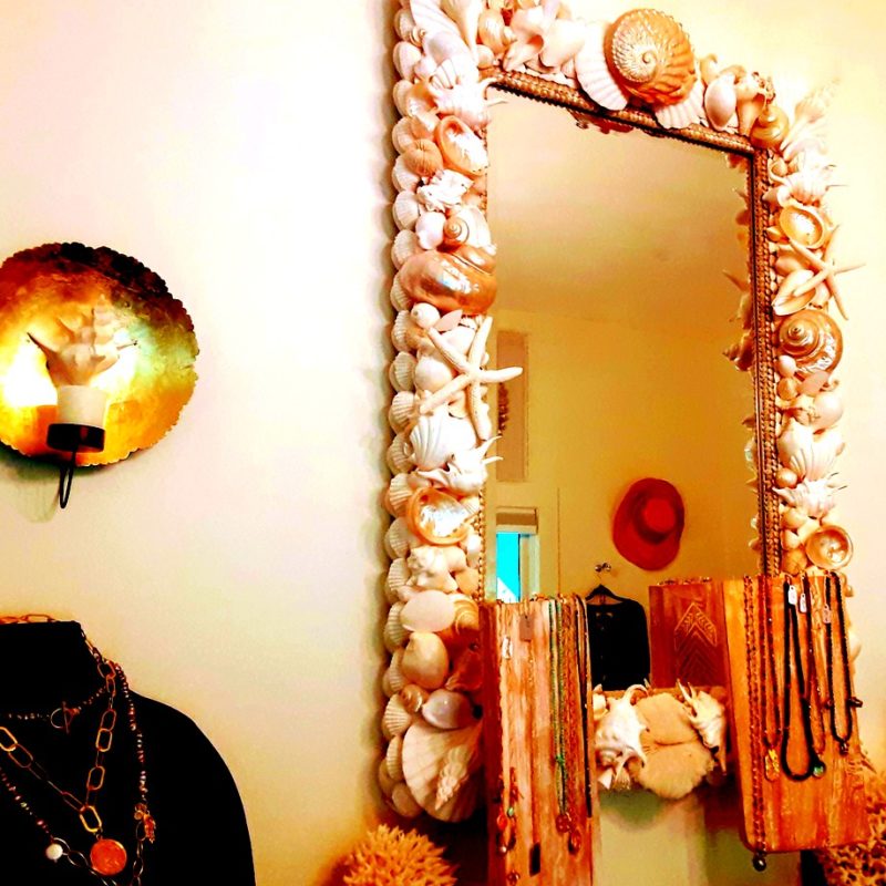 A shell mirror hangs on a wall