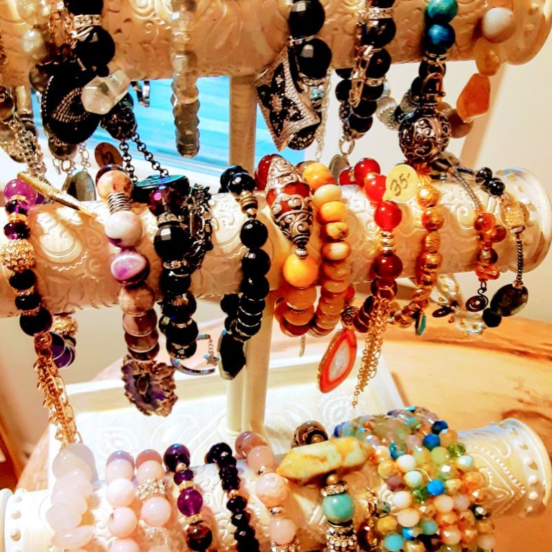 beaded bracelets are for sale on a wooden hanger